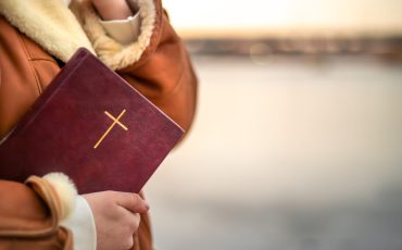 A woman holds the Bible in her hands in nature. Christianity concept. High quality photo. Copy space. Bible close up. Prayer, faith, Christianity, religion.